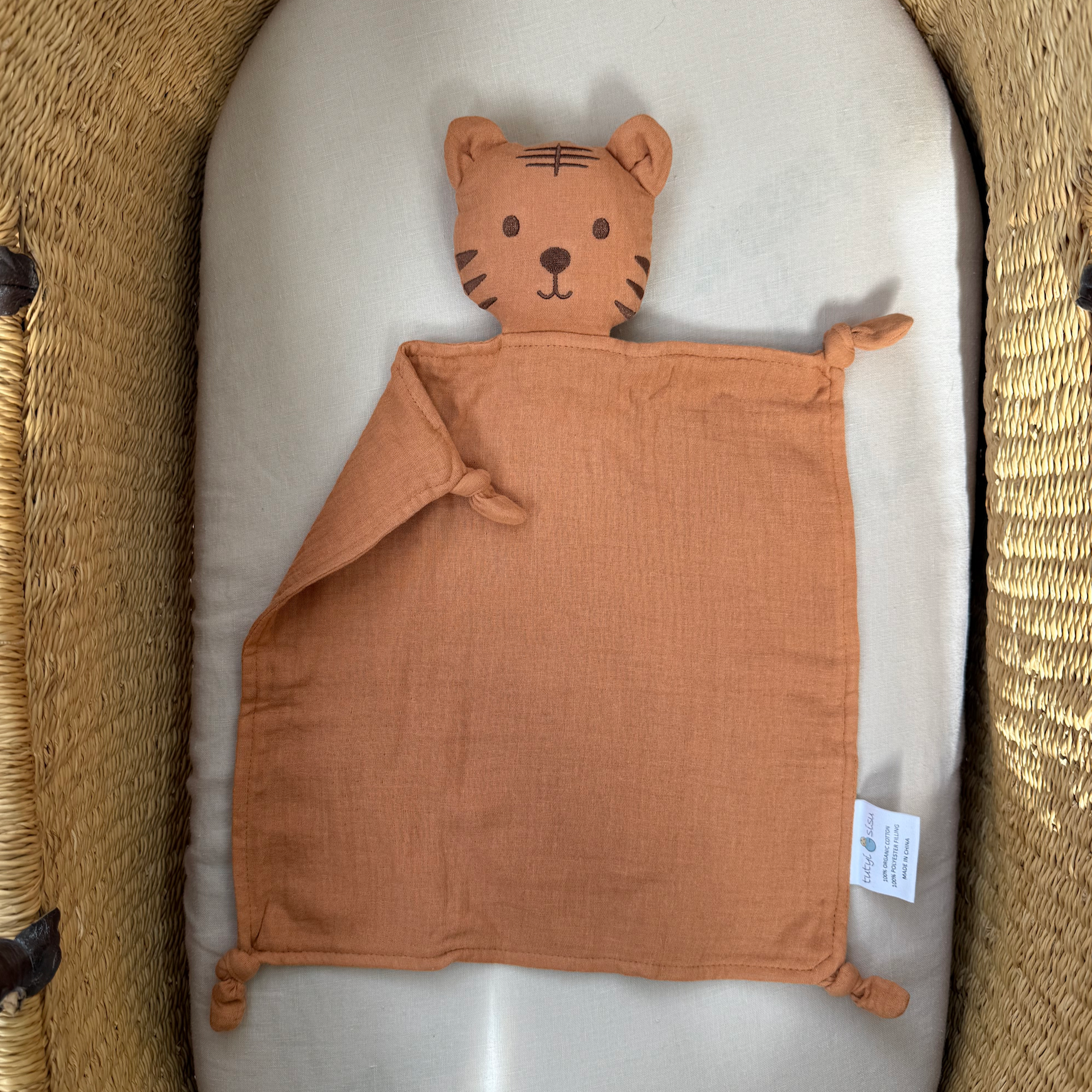 Orange tiger baby comfort blanket in a crib